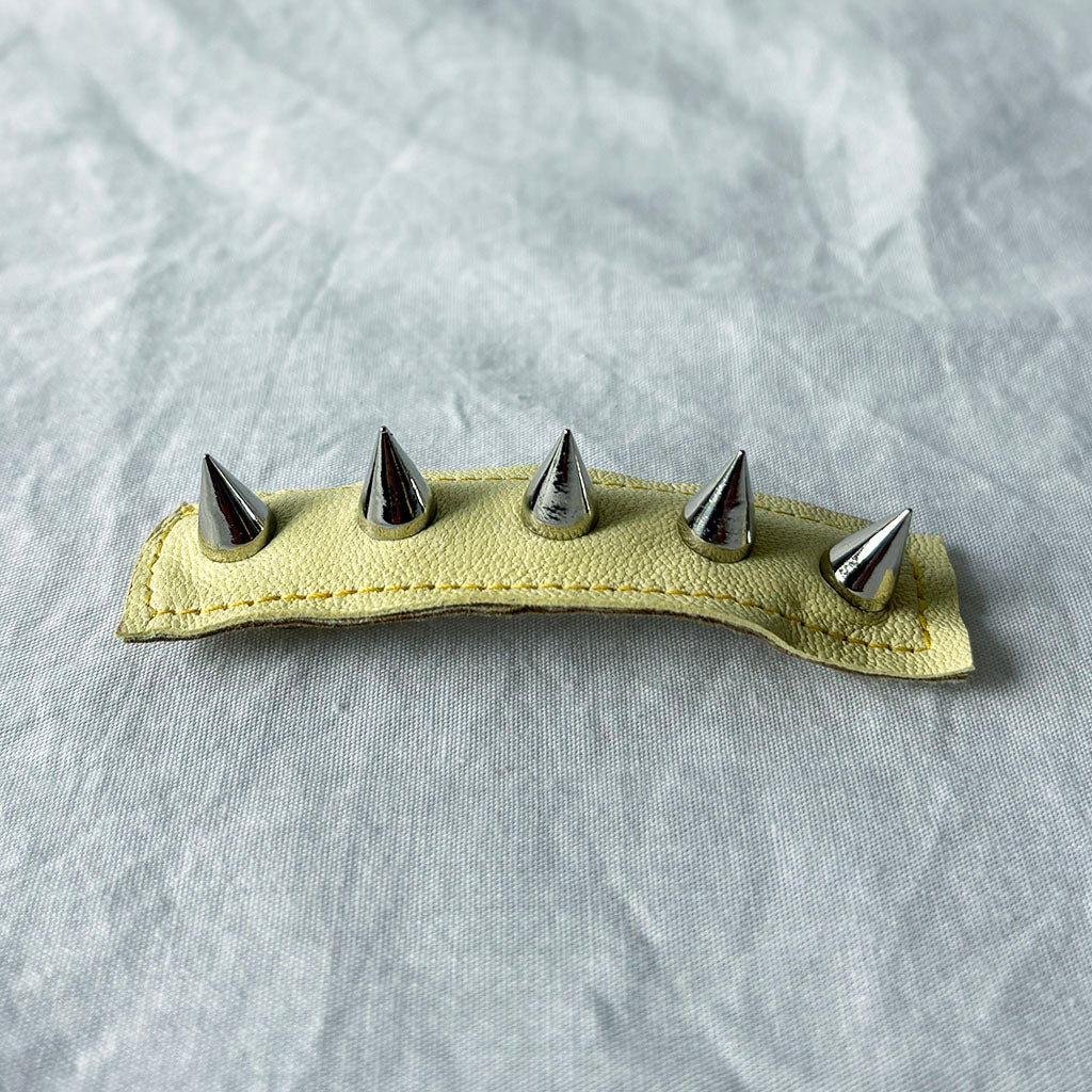 Leather barrette with metal spikes on a gray background