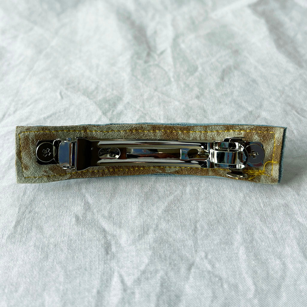 Metallic hair clip on a textured white background