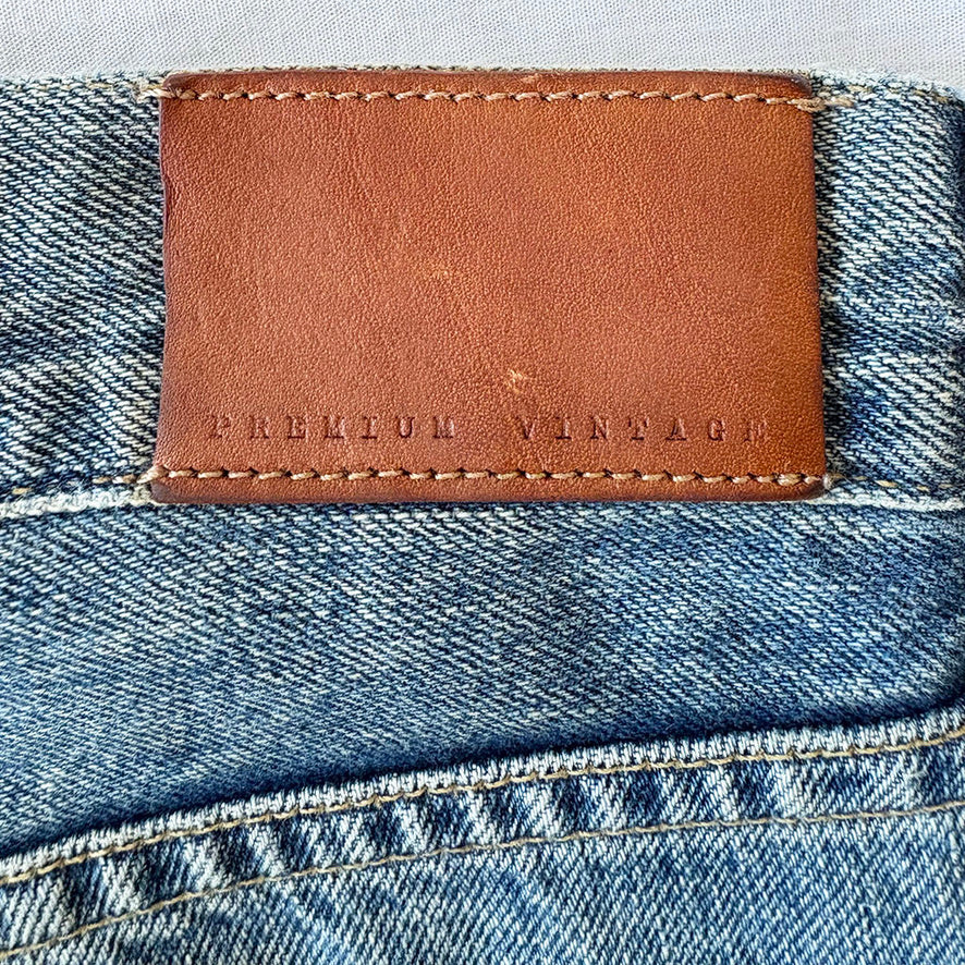 Close-up of a brown leather label on blue denim fabric with 'PREMIUM VINTAGE' text.