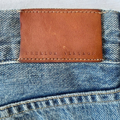 Close-up of a brown leather label on blue denim fabric with 'PREMIUM VINTAGE' text.