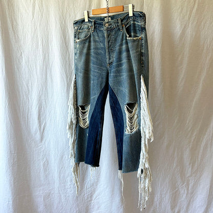 Distressed blue jeans with fringe on a white background