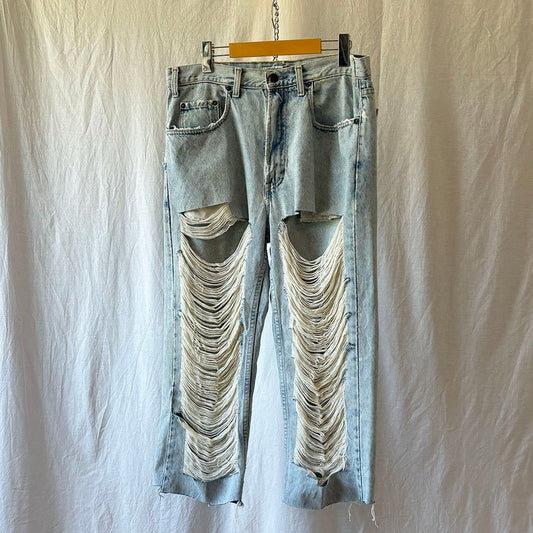 Distressed light blue jeans on a hanger against a plain background