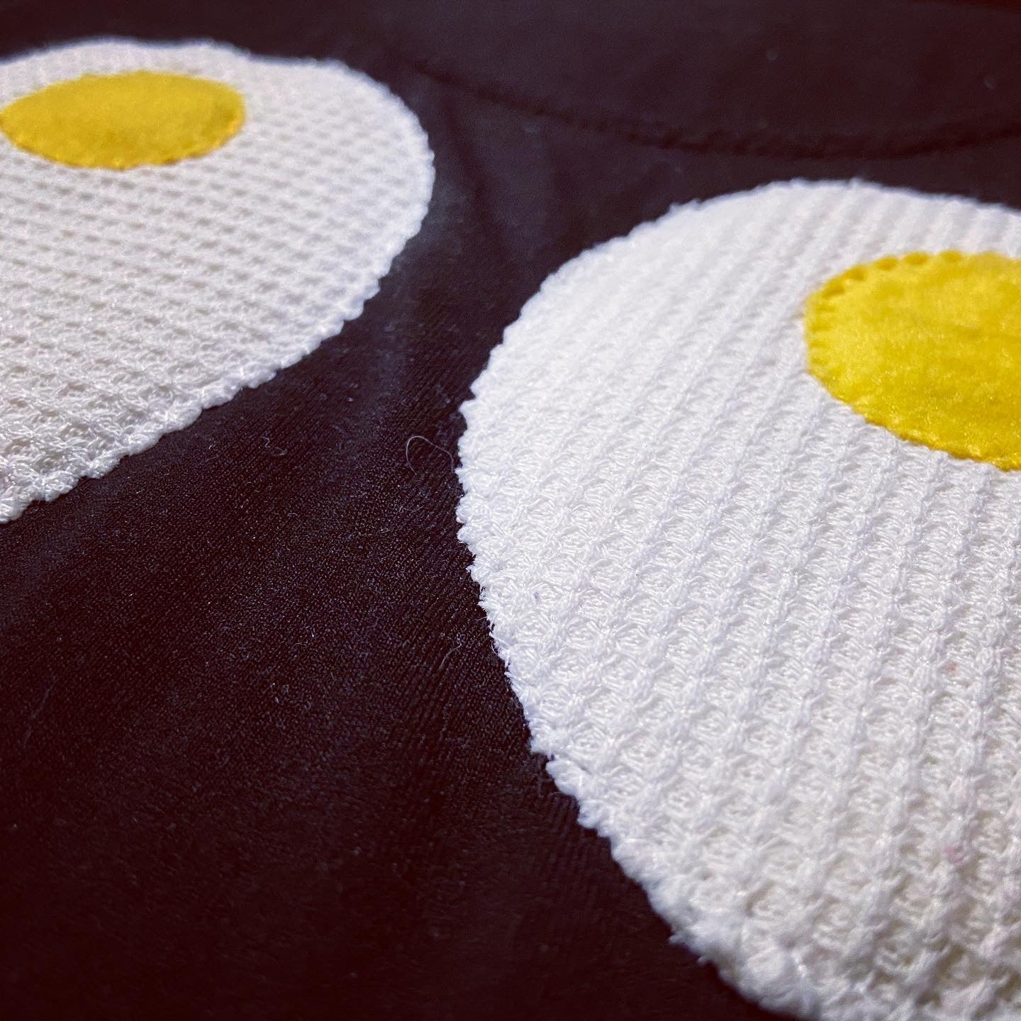 Two knitted eggs with yellow centers on a dark background