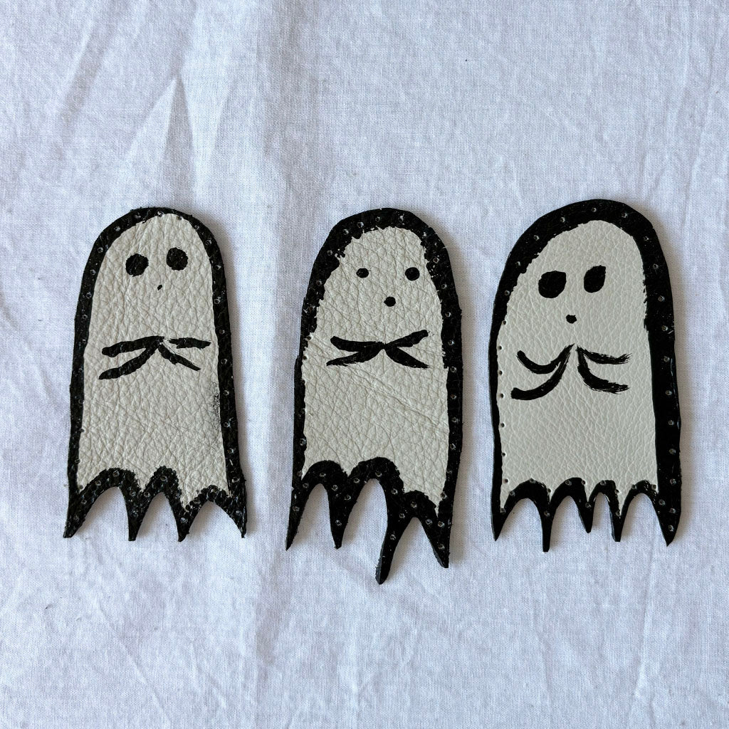 Three ghost-shaped leather patches on a white background