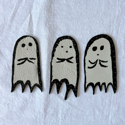 Three ghost-shaped leather patches on a white background