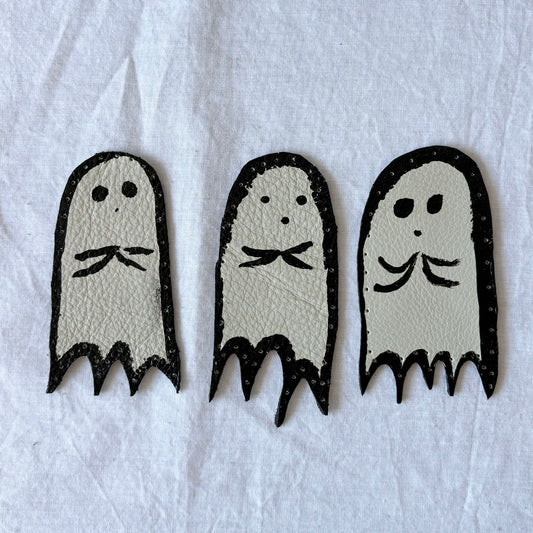 Three ghost-shaped leather patches on a white background