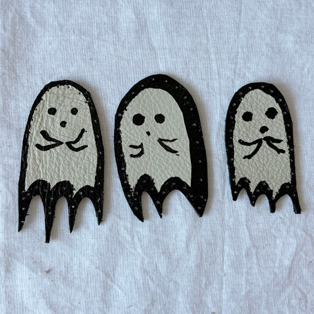 Three ghost-shaped leather patches with black outlines on a white background