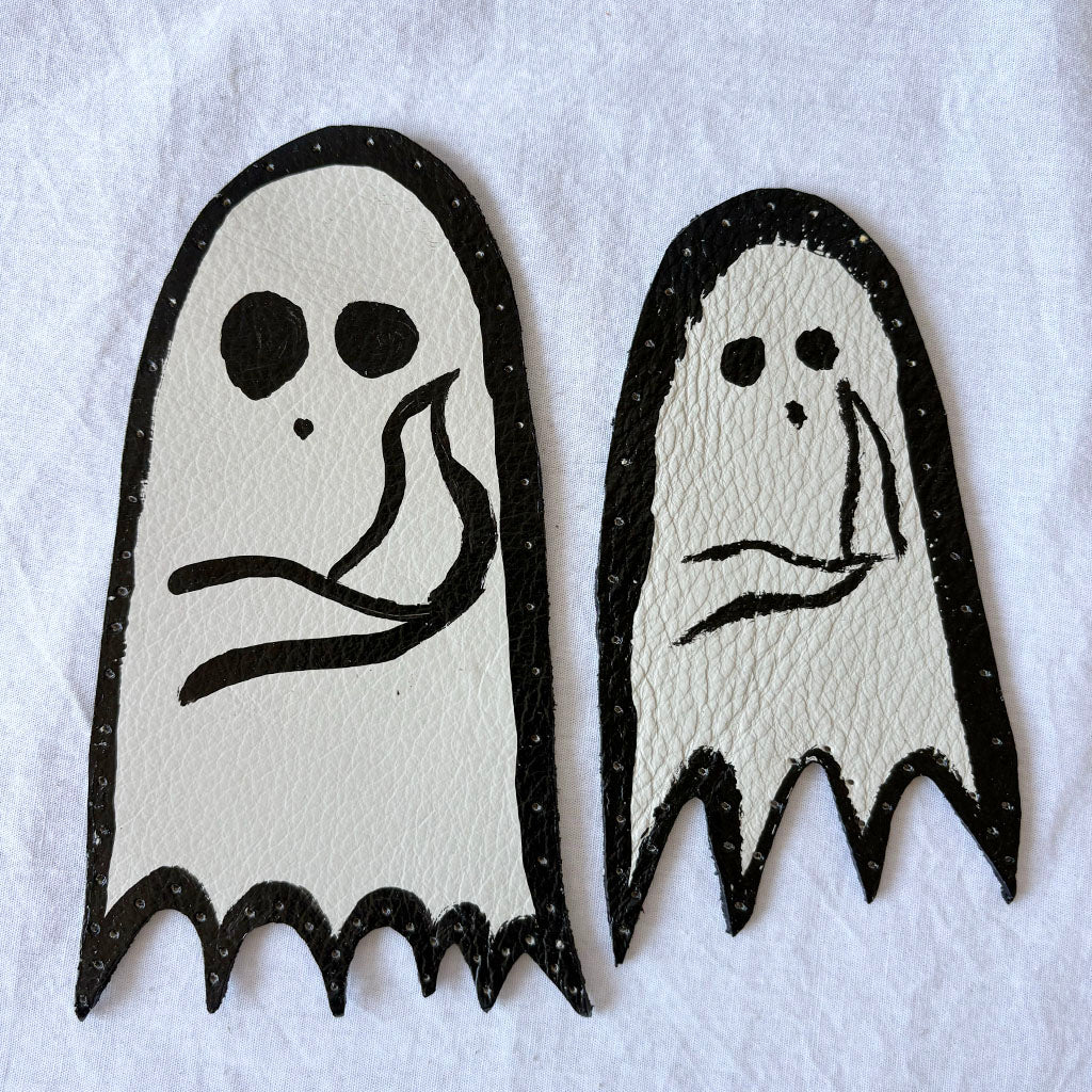 Two ghost-shaped leather patches with holes punched around the edges
