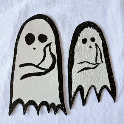 Two ghost-shaped leather patches with holes punched around the edges
