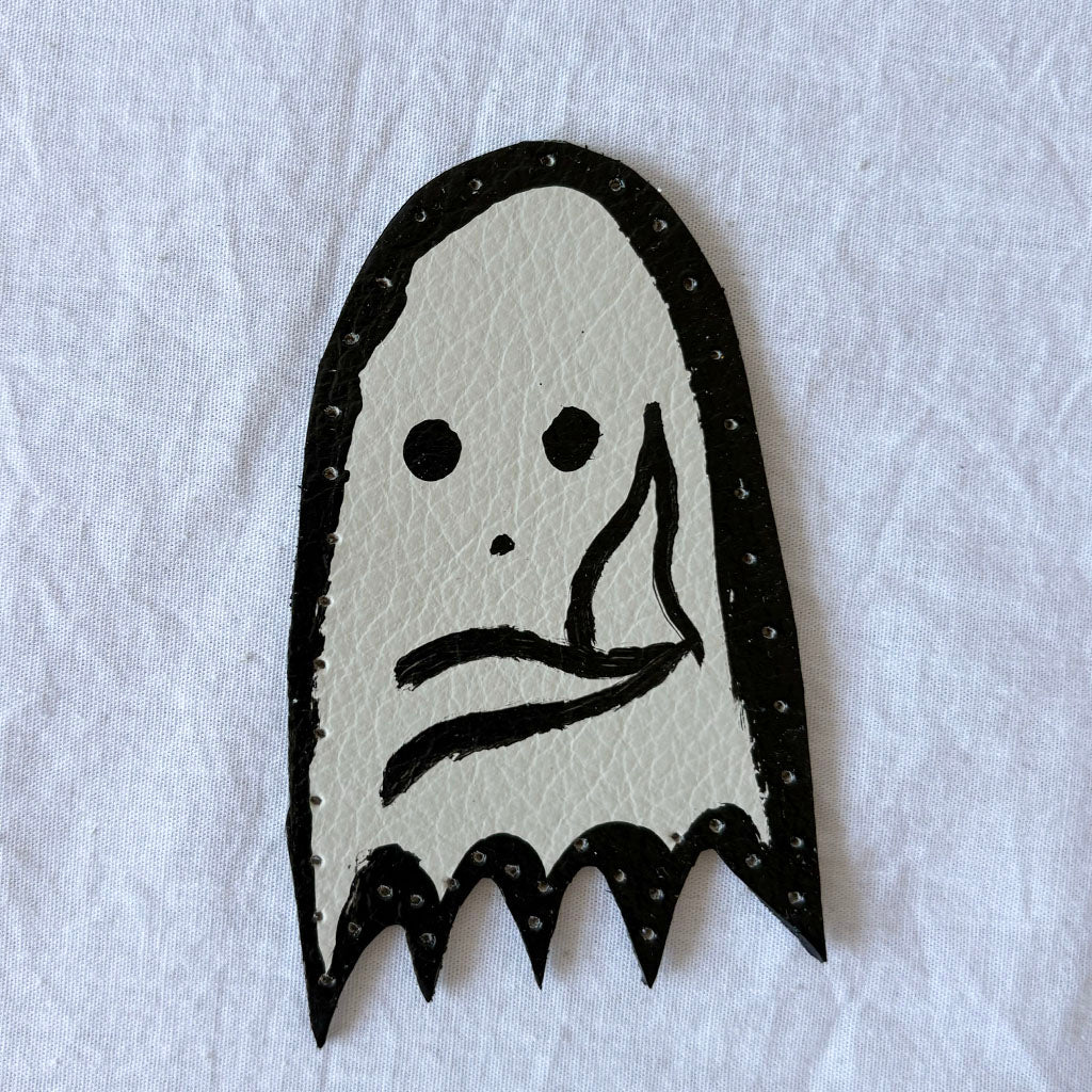 Ghost-shaped white leather patch with black outline on a white background