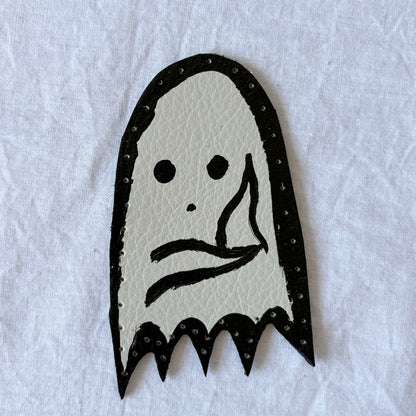Ghost-shaped white leather patch with black outline on a white background