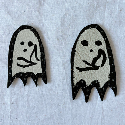 Two ghost-shaped white leather patchs with black outlines on a light gray background