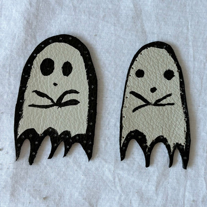 Two ghost-shaped white leather patches with black outlines on a white background