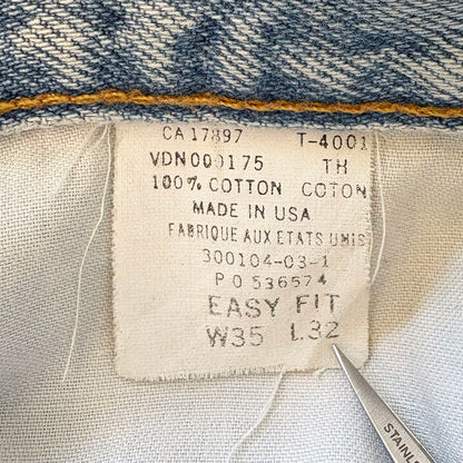 Fabric tag on denim fabric with text and a pair of scissors.