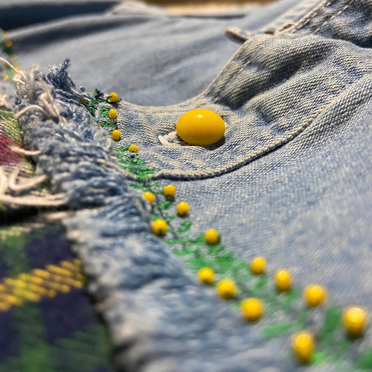 Close-up of a denim fabric with yellow buttons and embroidery
