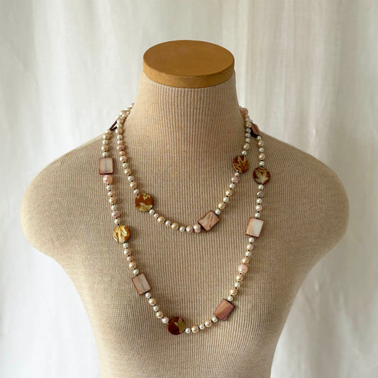 Necklace with pearls and shell and acrylic accents on a mannequin bust against a white background