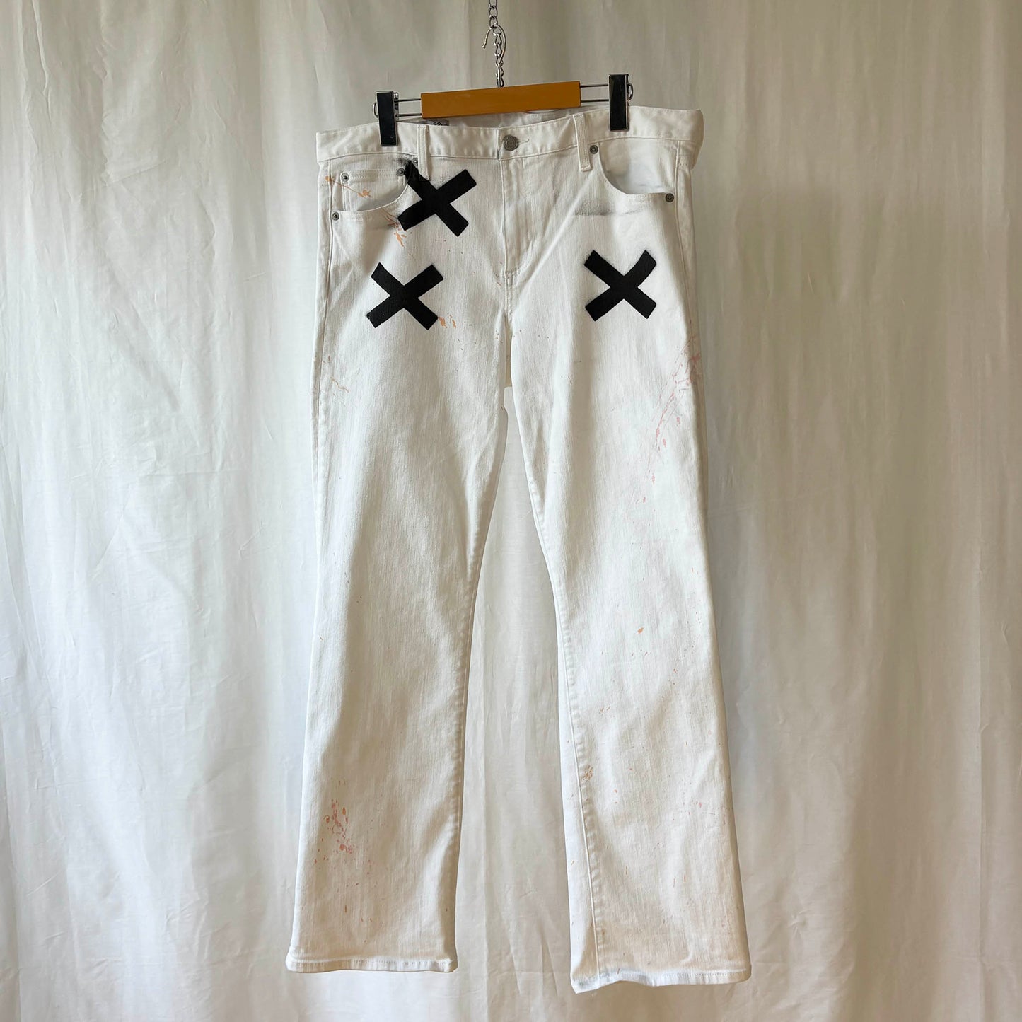 White pants with 3 black 'X' marks on a hanger against a white background