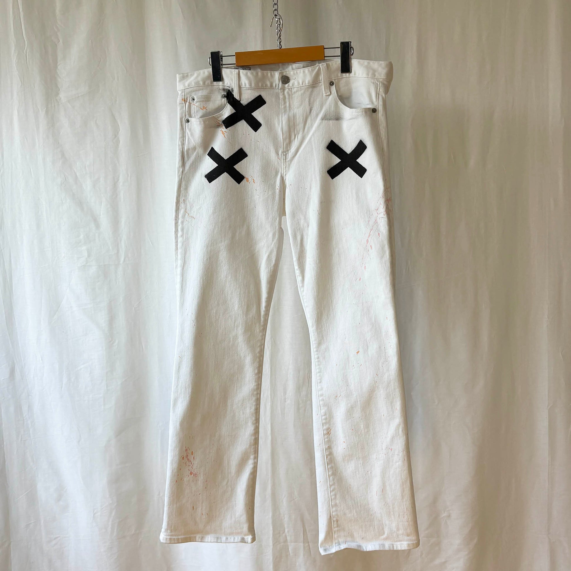 White pants with 3 black 'X' marks on a hanger against a white background
