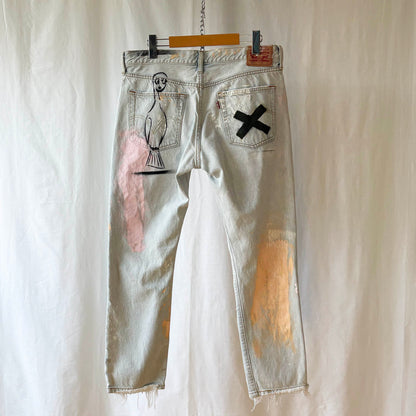 Distressed denim jeans with spray paint stencils on a white background