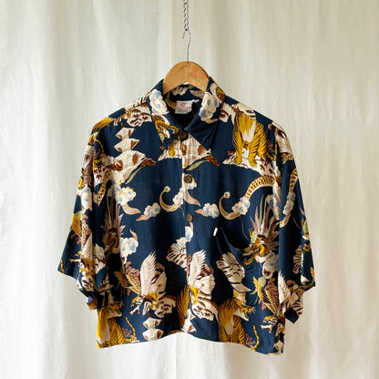 Tiger and dragon patterned shirt on a hanger against a white curtain background