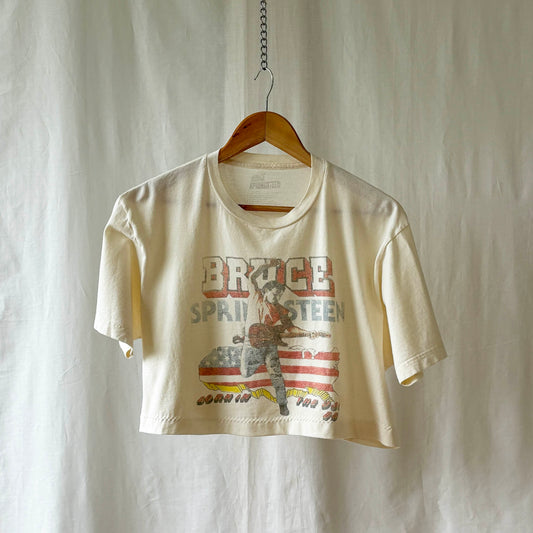 Off white Bruce Springsteen Born in the USA t-shirt  on a wooden hanger against a white background