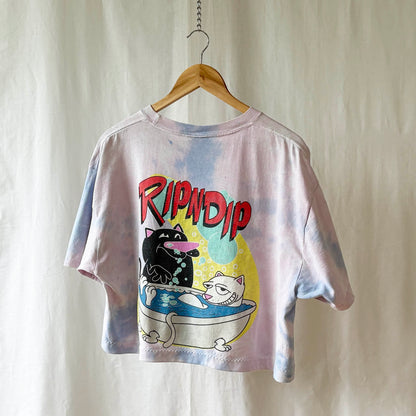 Tie-dye t-shirt with a cat farting in a tub an a brand logo on a wooden hanger against a plain background