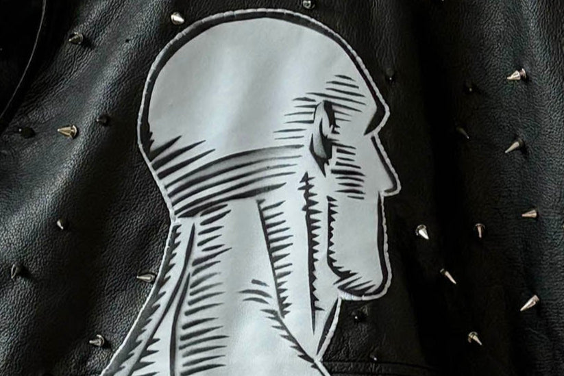 Studded black leather jacket with blue leather Dr. Manhattan patch.