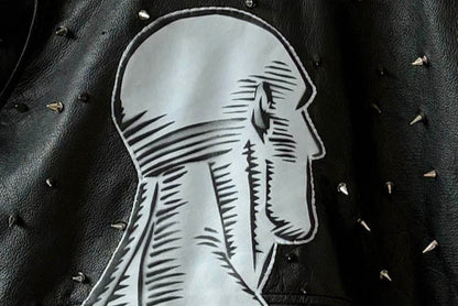 Studded black leather jacket with blue leather Dr. Manhattan patch.