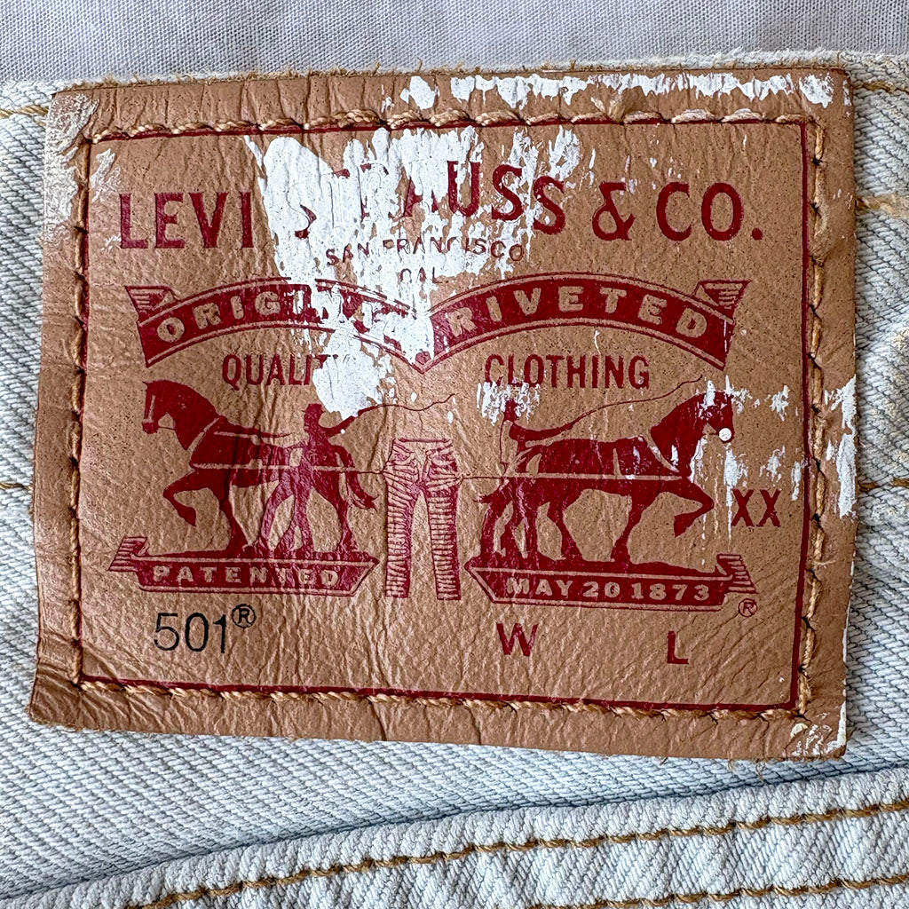 Levi's 501 label on denim fabric with visible wear and tear.