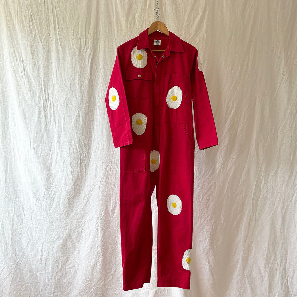 Red jumpsuit with white egg designs on a textured white background