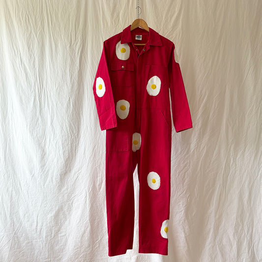 Red jumpsuit with white egg designs on a textured white background