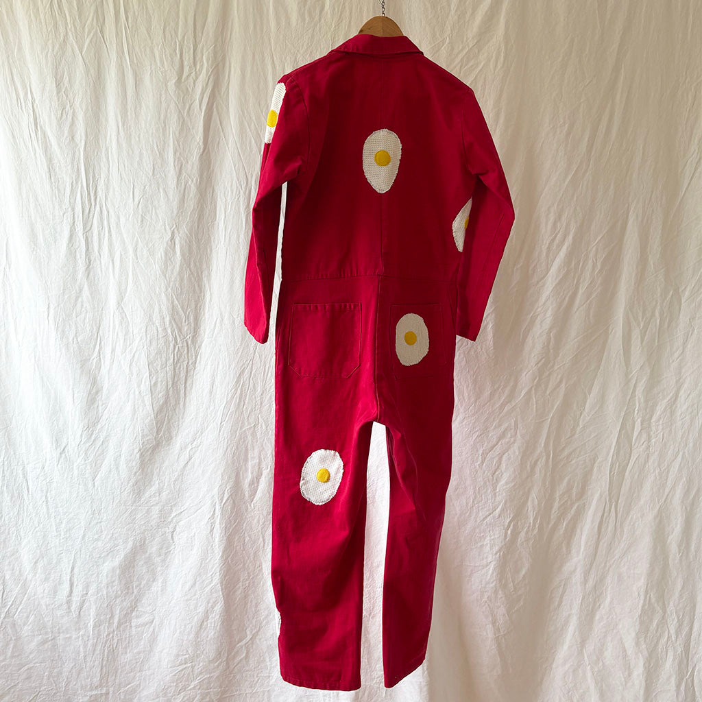 Red jumpsuit with white egg designs on a textured beige background