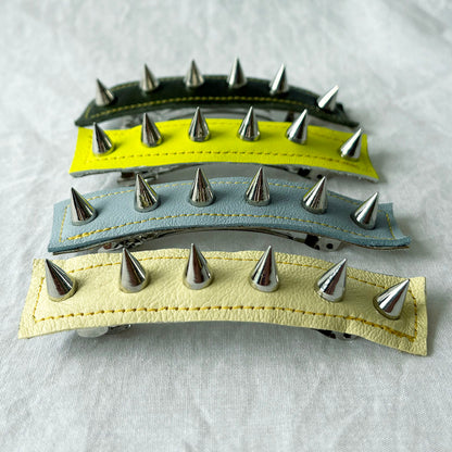 Three hair clips with metal spikes on a light gray background