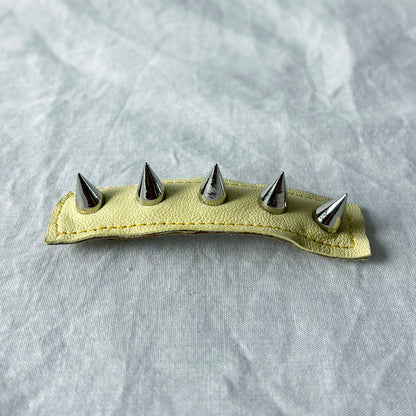 Leather barrette with metal spikes on a gray background