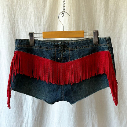 Denim skirt with red fringe on a hanger against a white background