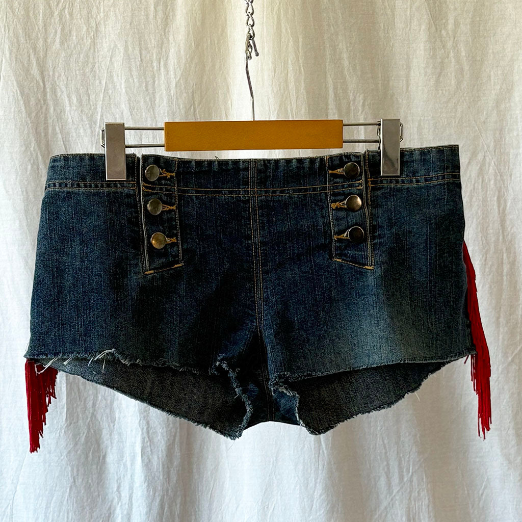 Blue denim shorts with red fringe visible at the sides on a hanger against a white background