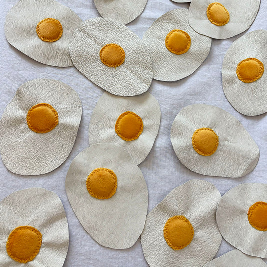 leather eggs with velvet yokes arranged on a white surface.