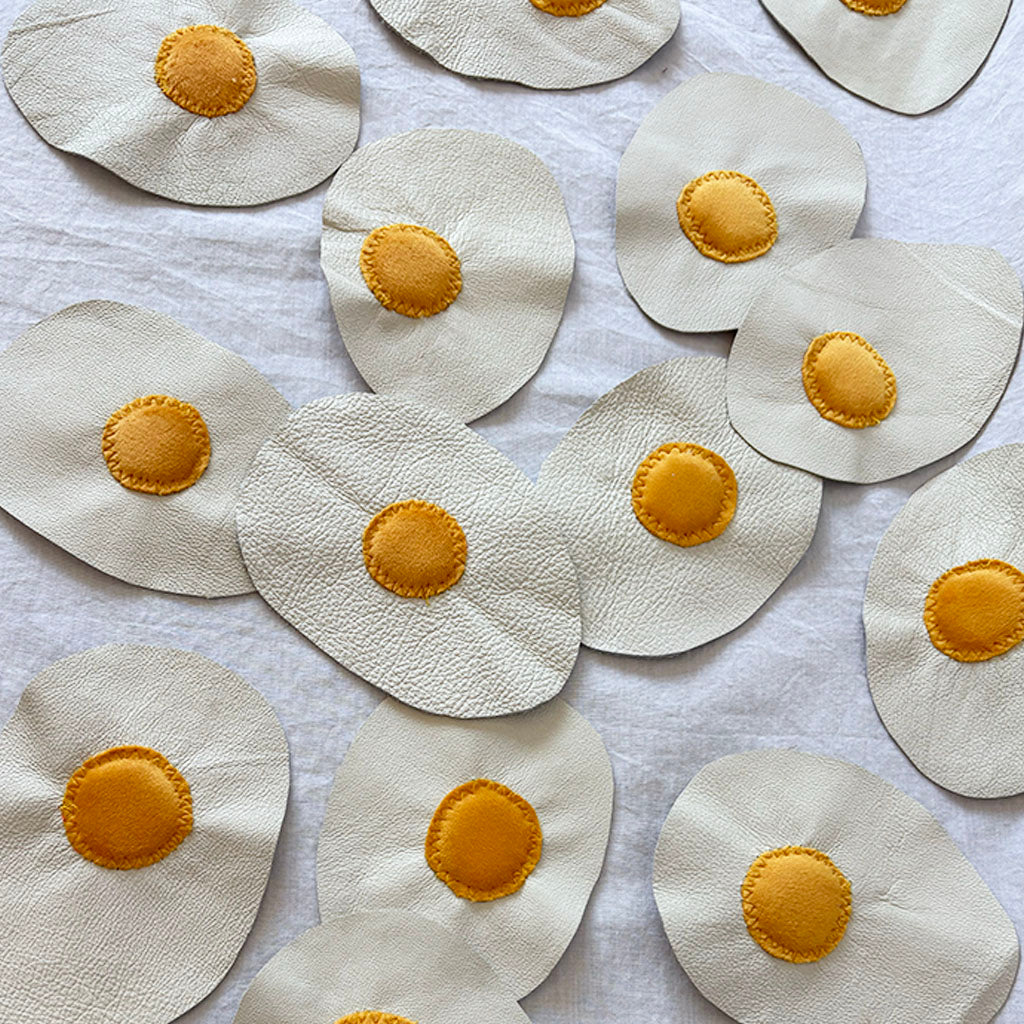 leather eggs with yellow velvet yokes arranged on a white surface