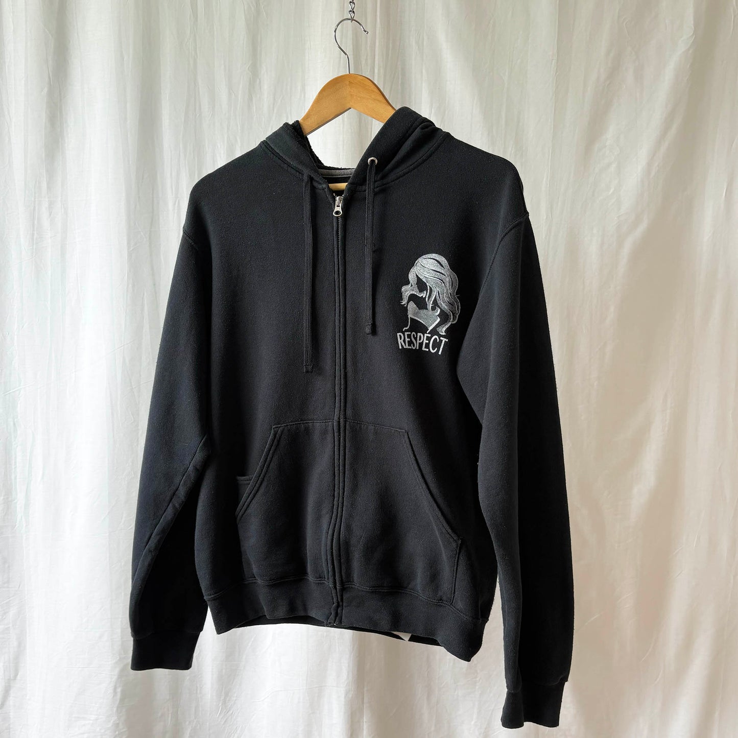 Black hoodie with a graphic design on a hanger against a white background