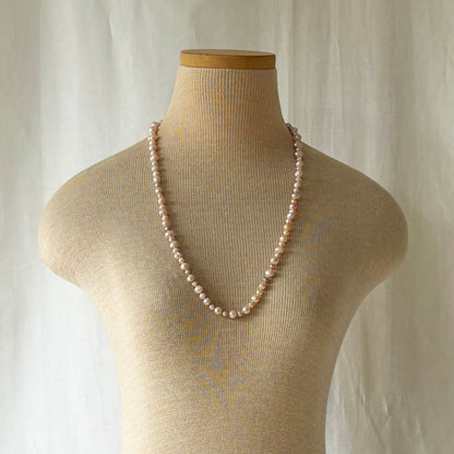 Pearl necklace on a mannequin bust against a neutral background