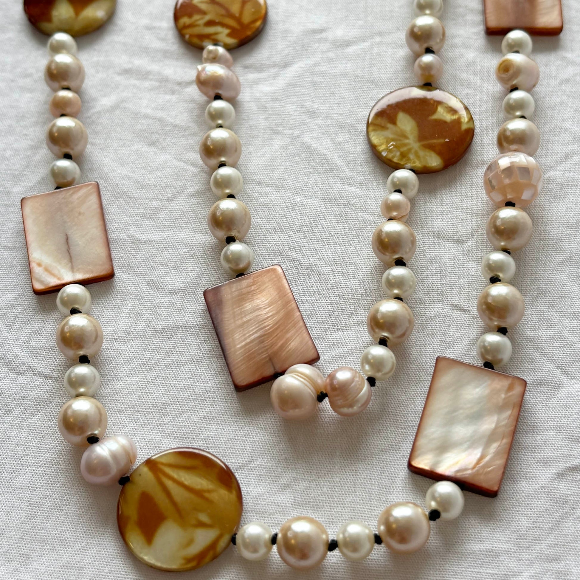 Necklace with pearls and shell and acrylic accent beads on a light fabric background