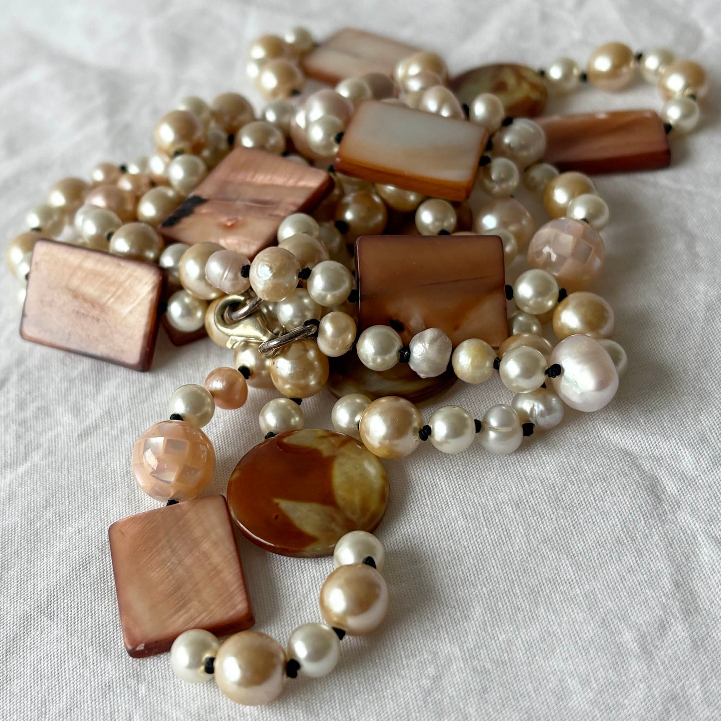 Pearl necklace with shell and acrylic beads on a light fabric background