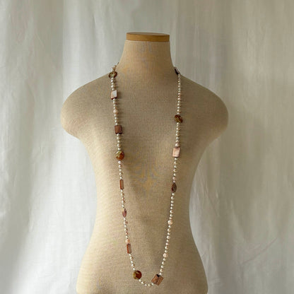 Pink pearl necklace with shell and acrylic accents on a mannequin against a plain background