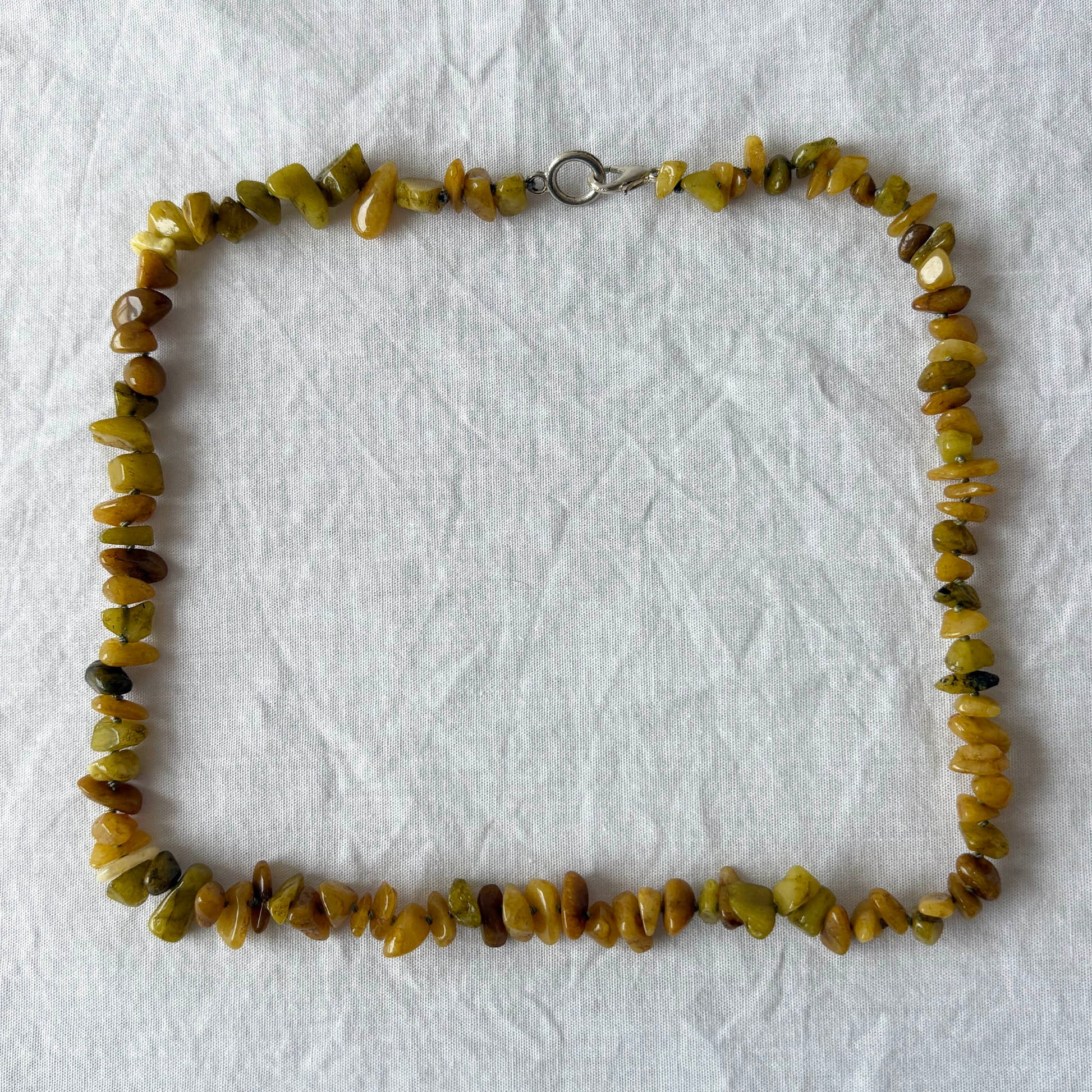 Necklace with green stone beads on a white fabric background