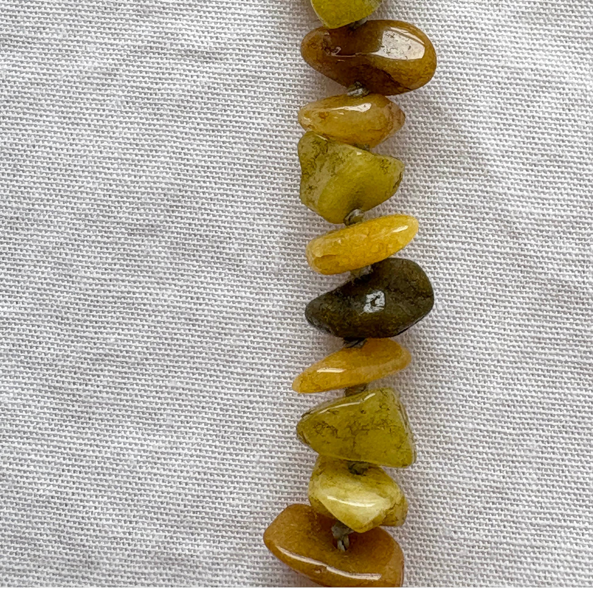 String of green stone beads on a textured white background