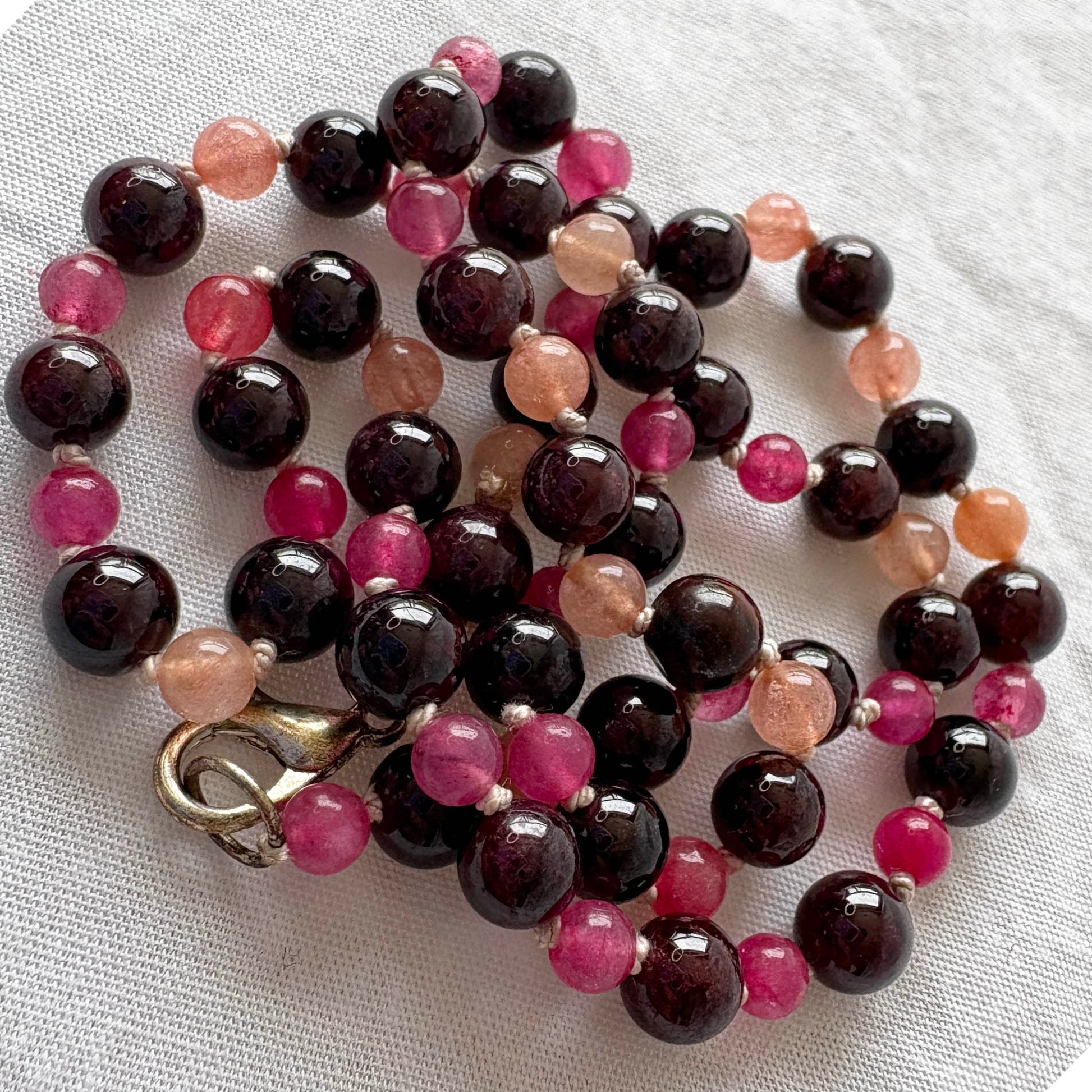 Necklace with multicolored beads on a white fabric background