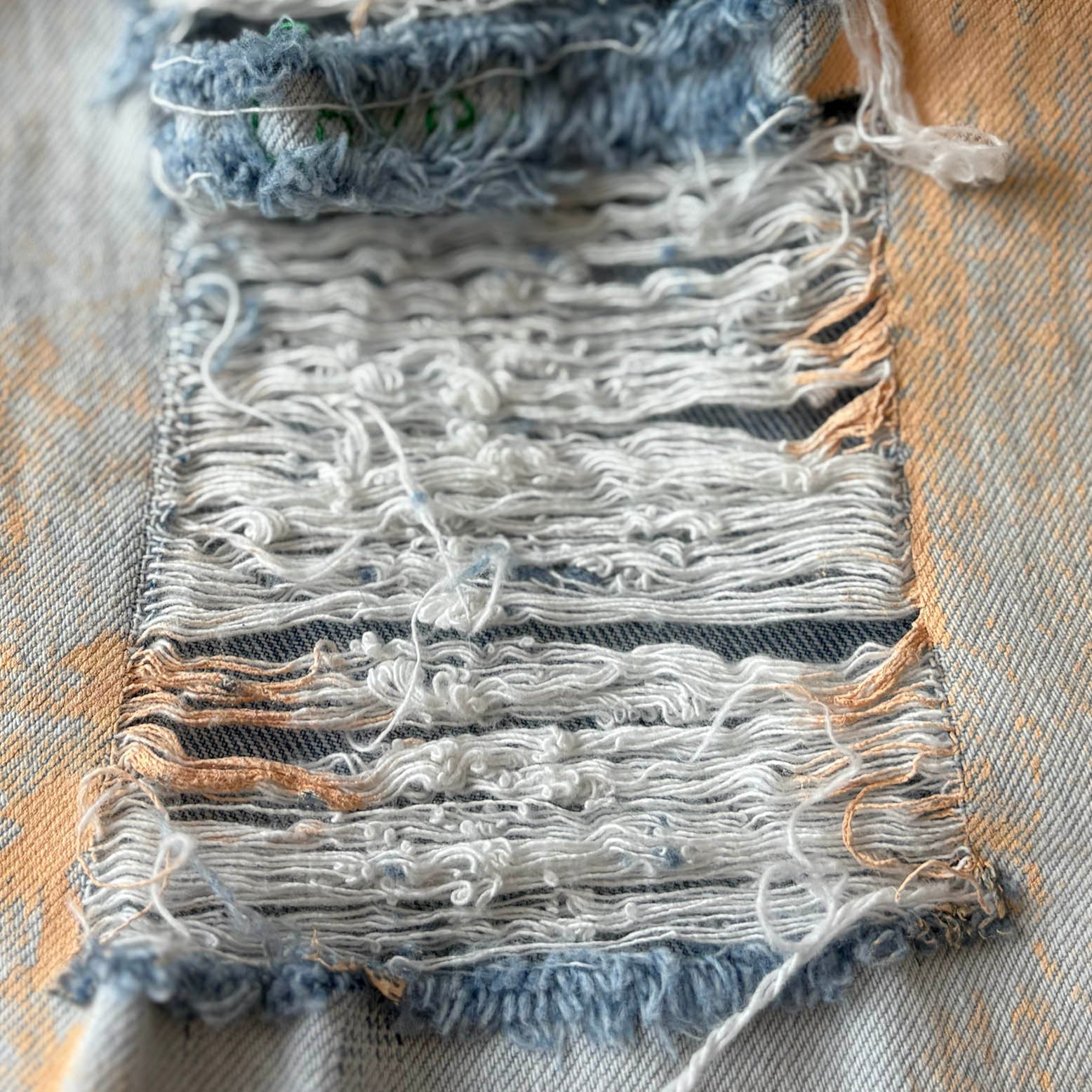 Textile sample with frayed edges on a textured fabric background
