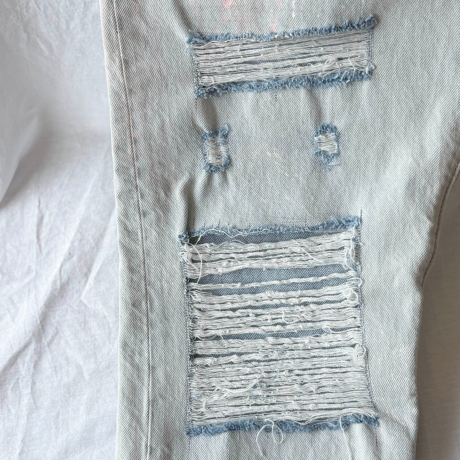 Close-up of distressed denim fabric with frayed edges on a white background