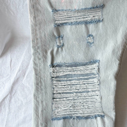 Close-up of distressed denim fabric with frayed edges on a white background