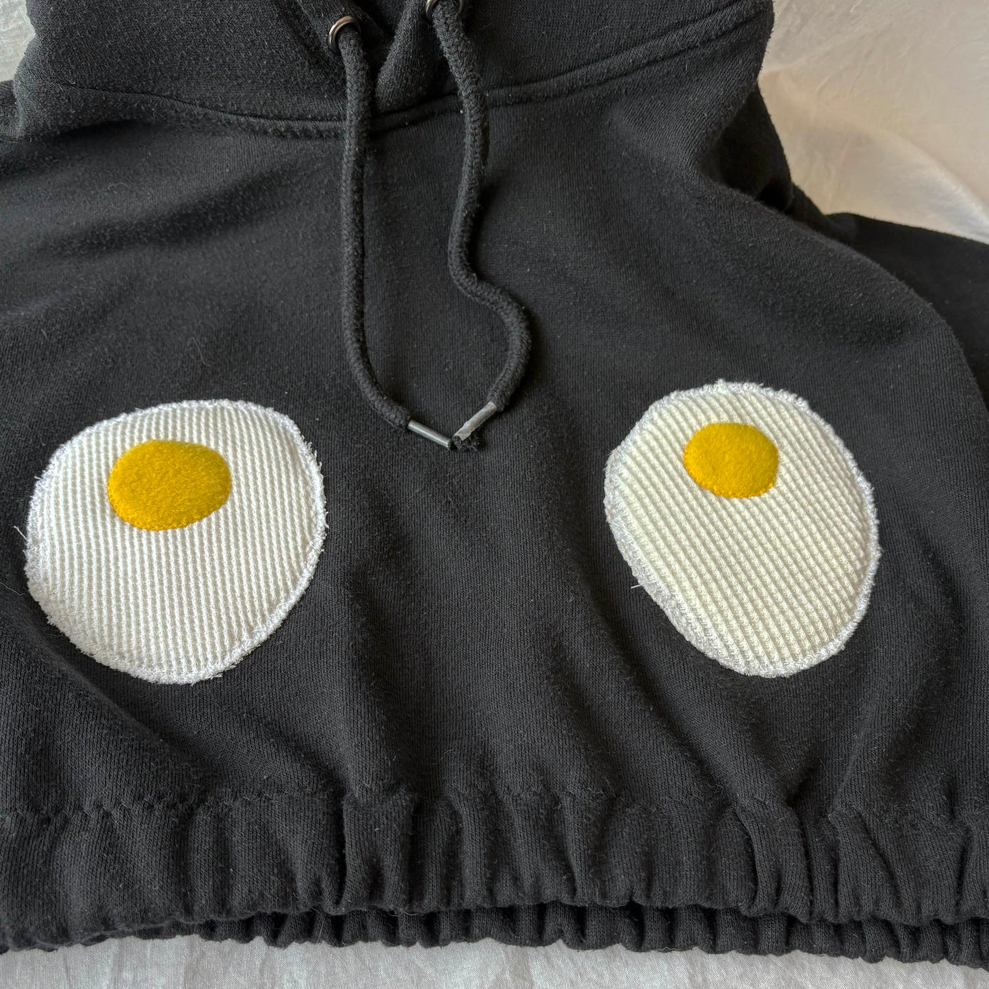Black hoodie with knitted eggs design on a light background